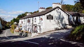 Un bâtiment blanc sur lequel on peut lire l’enseigne « Brown Horse Inn », ce qui indique qu’il s’agit d’un établissement public proposant un bar et des repas.