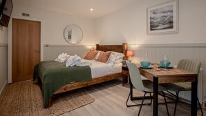 Une chambre à coucher comprenant un lit, une table de chevet, une lampe, ainsi qu’un coin repas avec des chaises et une table.