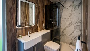 Une salle de bain moderne avec un meuble-lavabo en marbre, un grand miroir, une douche et des toilettes.