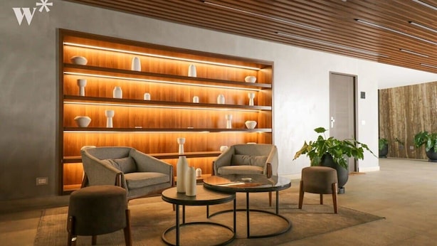 A modern lobby with a wooden wall display, comfortable seating, and a large potted plant. - w* | Fantastic 2BR with Balcony in Miraflores (Miraflores)
