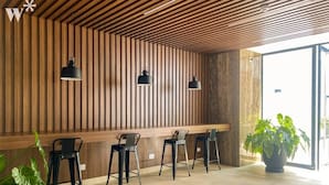 A modern interior with a wooden slatted ceiling, a long wooden bench, and three black metal chairs. - w* | Fantastic 2BR with Balcony in Miraflores (Miraflores)