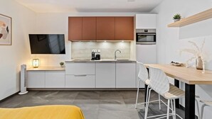 Una cocina moderna con armarios blancos, encimera de madera y horno empotrado.