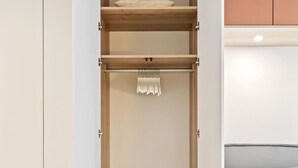 Un vestidor con estantes de madera, barra para colgar ropa y un banco.