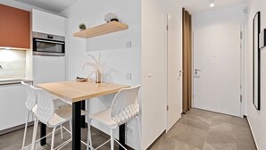 Una cocina moderna con armarios blancos, una mesa de comedor de madera y dos sillas blancas.