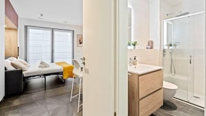 Un dormitorio moderno con una cama, una silla y un ventanal grande.