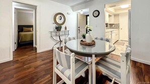 Spiseområde med et rundt bord, stole, en ventilator i loftet og et ur på væggen.