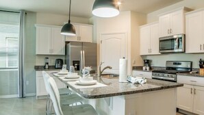 A modern kitchen with a central island, stainless steel appliances, and pendant lighting.