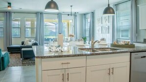 A modern kitchen with white cabinets, a granite countertop, and pendant lighting.