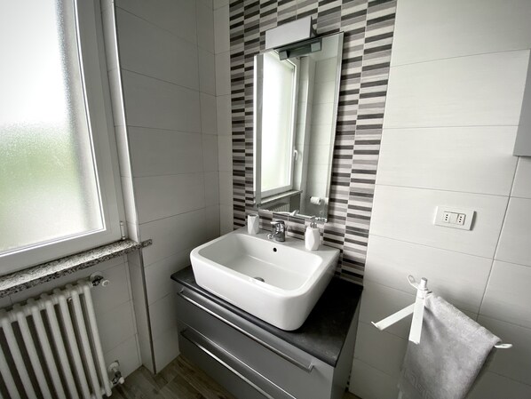 A bathroom with a white sink, a mirror, a towel rack, and a window.