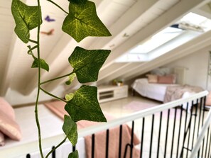 A room with a sloped ceiling, a bed with pink bedding, and a white railing. - Villa Gioia, with a pool in Monferrato (Piemonte)