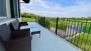 Un balcone con mobili in vimini e vista su un paesaggio verde.