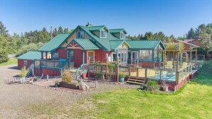 A large, multi-story house with a green roof, a covered porch, and a fenced-in swimming pool area. - Dogs Ok, Large Deck, BBQ, Fire pit, Close to Beach (Brock) (Long Beach)