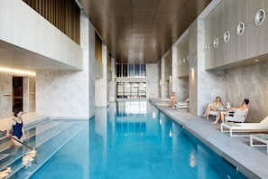 An indoor swimming pool with a clear view of the pool area, including the poolside seating and the pool's edge. - A Cozy 2BR Apt for 6 Next to Southern Cross (Melbourne)