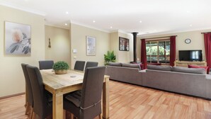 A modern living room with a dining area, a sofa set, a TV, and artwork on the walls.