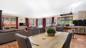 A modern living room with a dining table, sofas, and a kitchen area with a stove and microwave.