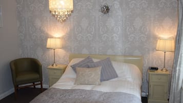 Une chambre à coucher bien rangée, avec un lit, deux lampes de chevet, une chaise et un élément décoratif mural.