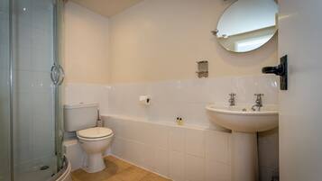 Un baño con cabina de ducha de vidrio, inodoro, bañera y lavabo con espejo.