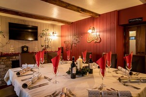 Una mesa de comedor preparada para una comida, con servilletas rojas, copas de vino y cubiertos.