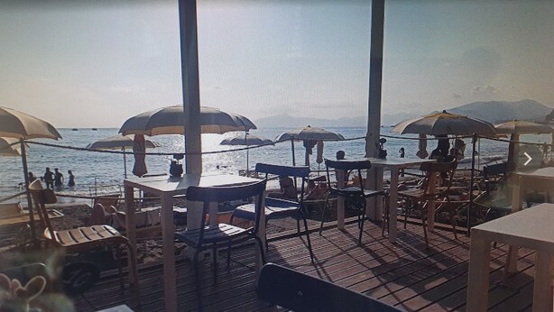 A beachside restaurant with outdoor seating and umbrellas, overlooking the sea. -  All Inclusive Deluxe Penthouse Studio (Sestri Levante)