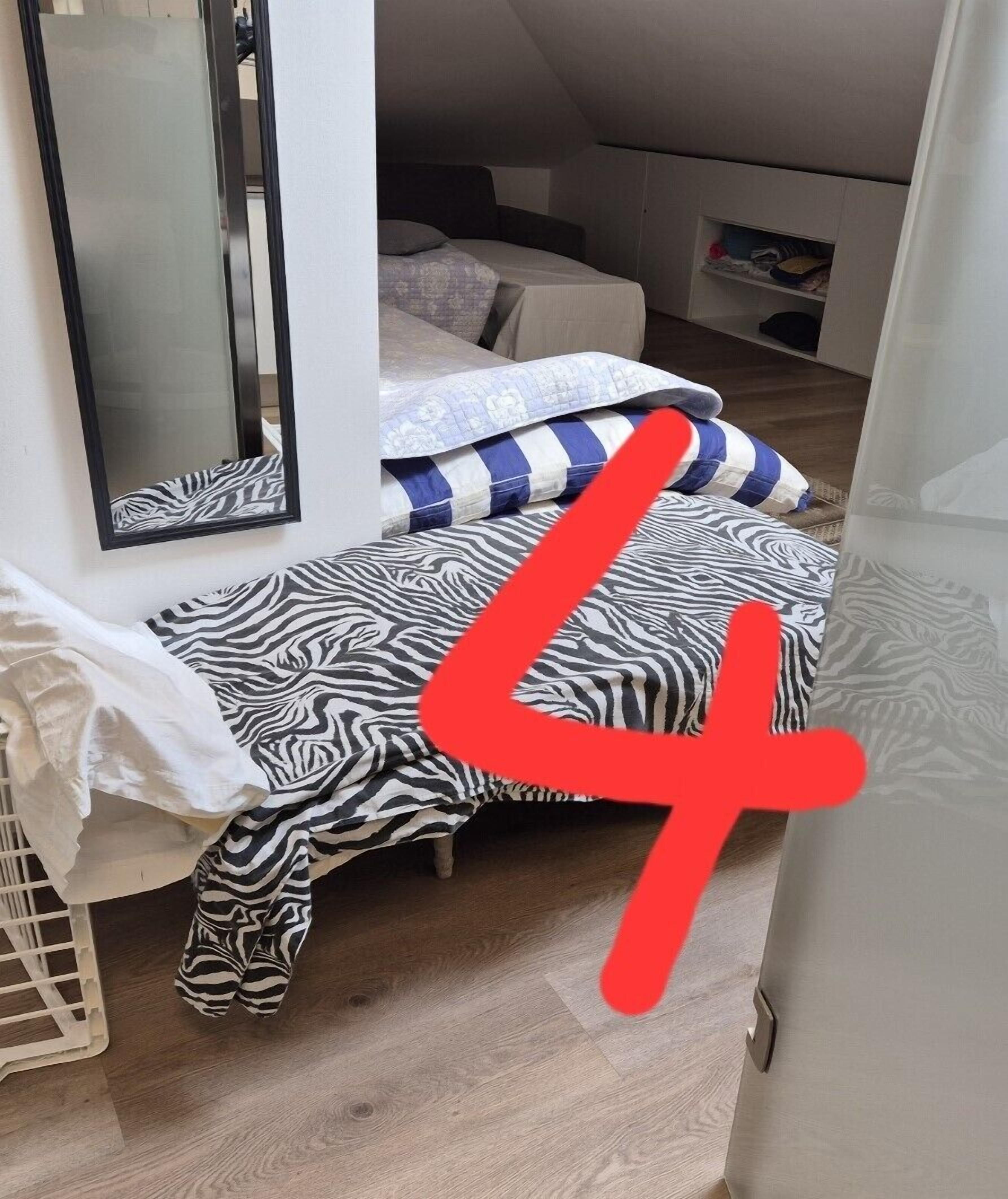 Una habitación pequeña y funcional con cama, espejo y armario.