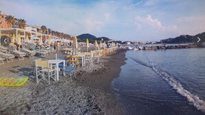 A beach with rows of beach chairs and umbrellas, a sandy shore, and a calm sea. -  All Inclusive Deluxe Penthouse Studio (Sestri Levante)