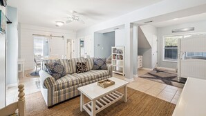 En rummelig opholdsstue med sofa, sofabord og reol.
