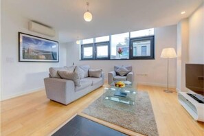 Relax in this stylish living room with a sofa, armchair, and flat-screen TV.