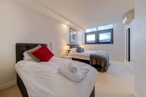 Cozy sleeping area with a large bed and a smaller adjacent bed, complete with a neatly folded towel.