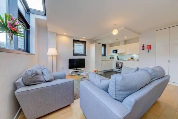 Relax in this tidy living space with a comfortable sofa, flat-screen TV, and compact kitchen area.