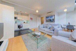 Relax in this stylish living space with a flat-screen TV, comfortable sofa, and a glass-top coffee table.