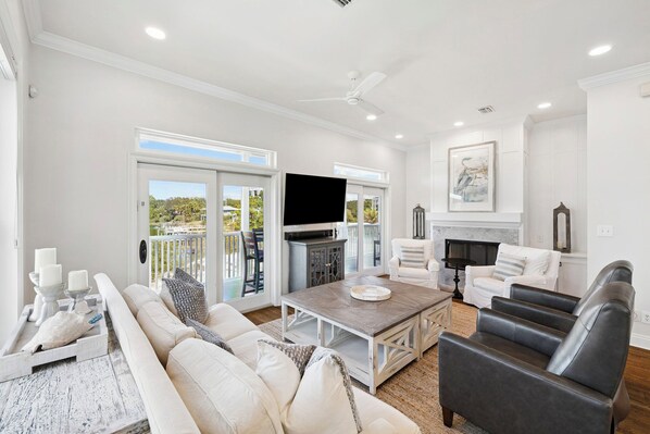 A spacious living room with a sofa, chairs, a coffee table, a TV, and a fireplace. - Stunning Lakefront Escape Steps to Beach w/ Pool, Spa, & Gulf-View Rooftop Deck (Seagrove Beach)