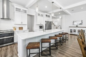 Une cuisine moderne avec des meubles blancs, des appareils en acier inoxydable et un îlot central doté de tabourets de bar.