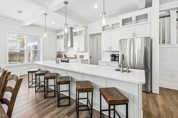 A modern kitchen with white cabinetry, stainless steel appliances, and a central island with stools.