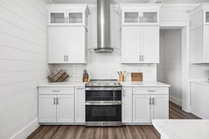A kitchen with white cabinetry, a stainless steel range hood, and a double oven. - Luxury home with private pool, outdoor kitchen w/fireplace & deeded beach access (Seacrest Beach West)