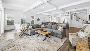 Ein geräumiges Wohnzimmer mit einer Eckcouch, einem Couchtisch und einem Essbereich mit Stühlen.