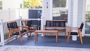 A deck with wooden furniture and a pool.