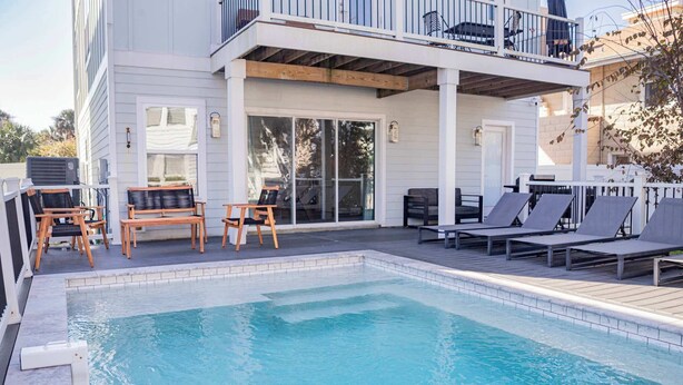 A pool area with lounge chairs and a covered deck.