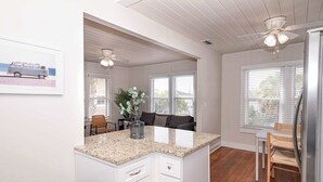 A kitchen with white cabinets, a granite countertop, and a ceiling fan.