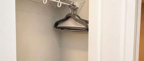 Un placard avec une porte blanche, une étagère blanche fixée au plafond et une tringle pour suspendre les vêtements.