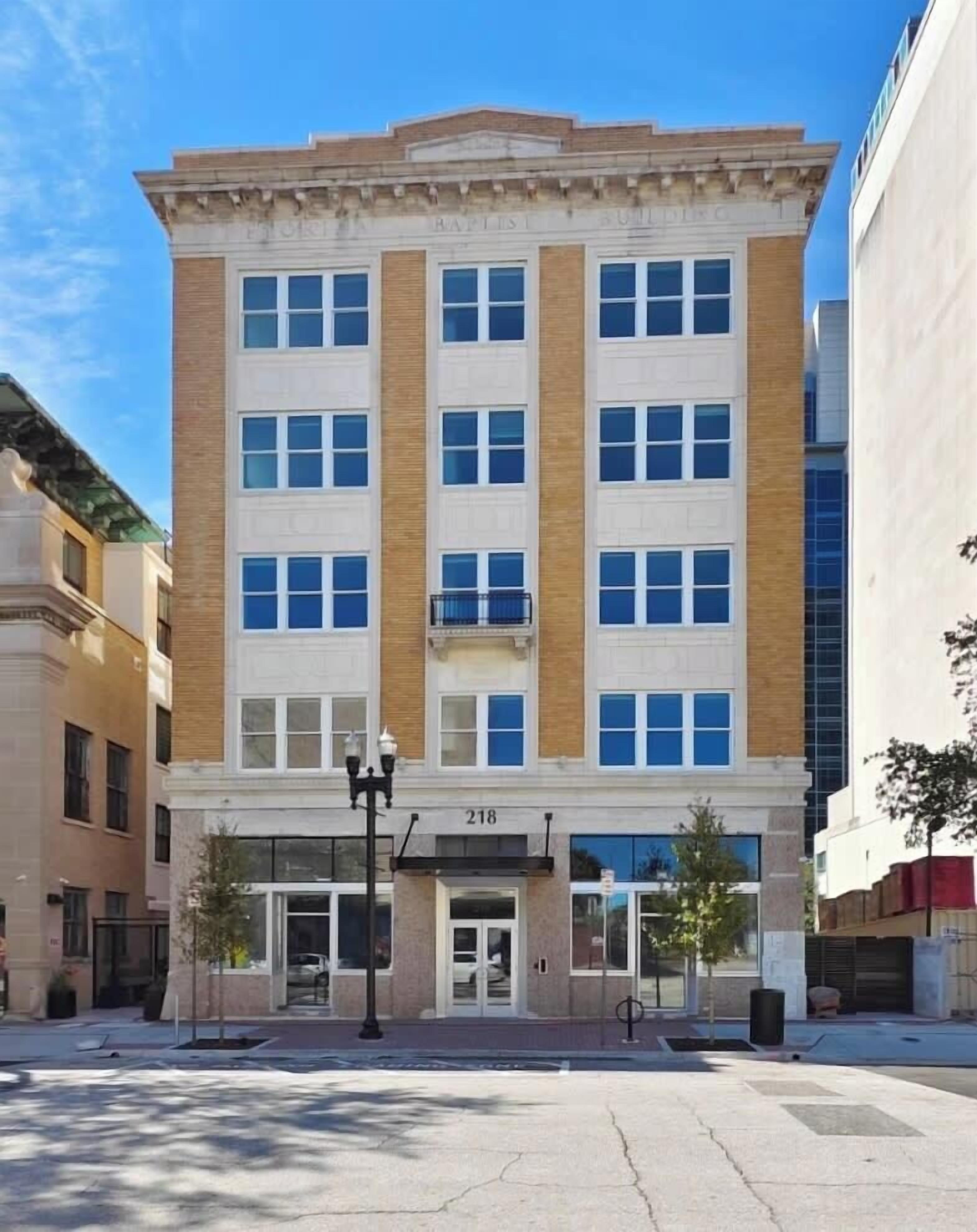 A multi-story building with a classic architectural style, featuring a central entrance with a door and windows on each floor.