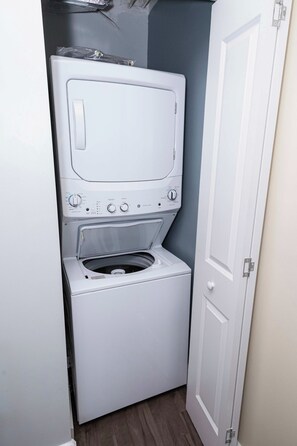Una lavadora compacta de color blanco, con carga frontal, panel de control y puerta.