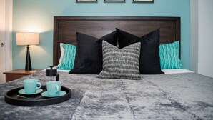 Een hotelkamer met een bed, nachtkastje, lamp en een dienblad met twee bekers.