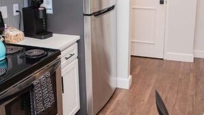 Een kleine keuken met een magnetron, fornuis, koelkast en koffiezetapparaat.