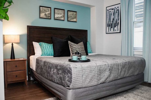 A bedroom with a large bed, a nightstand, a lamp, and artwork on the walls.