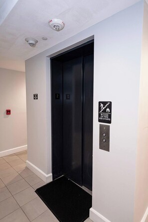 Un ascenseur équipé d’une alarme incendie et d’un panneau indiquant la sortie de secours, d’une sonnette et d’un indicateur d’étage.