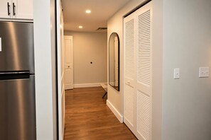 A hallway with a stainless steel refrigerator, a white door, and a set of white louvered closets. - Fun Cozy Studio Apts - 1 Mile to TIAA Bnk Fld! (Jacksonville)