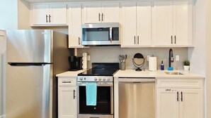 Una cocina moderna con electrodomésticos de acero inoxidable, armarios blancos y lavavajillas.