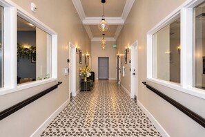A hallway with patterned flooring, a central light fixture, and doors on either side. - Fun Cozy Studio Apts - 1 Mile to TIAA Bnk Fld! (Jacksonville)