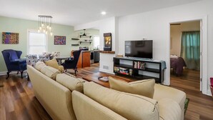 Un soggiorno con divano, televisione e zona pranzo con sedie e tavolo.