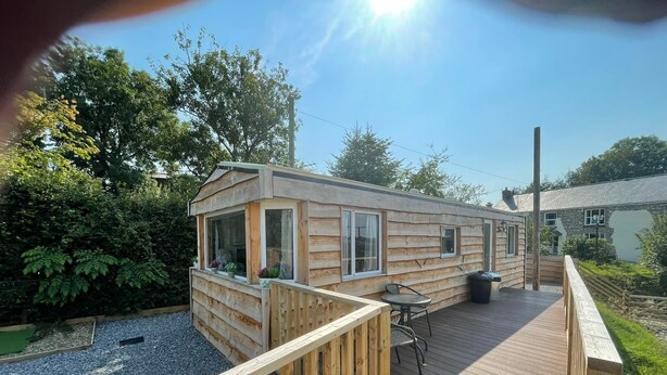 Eine Holzhütte mit einer Terrasse, einem Tisch und einem Stuhl.